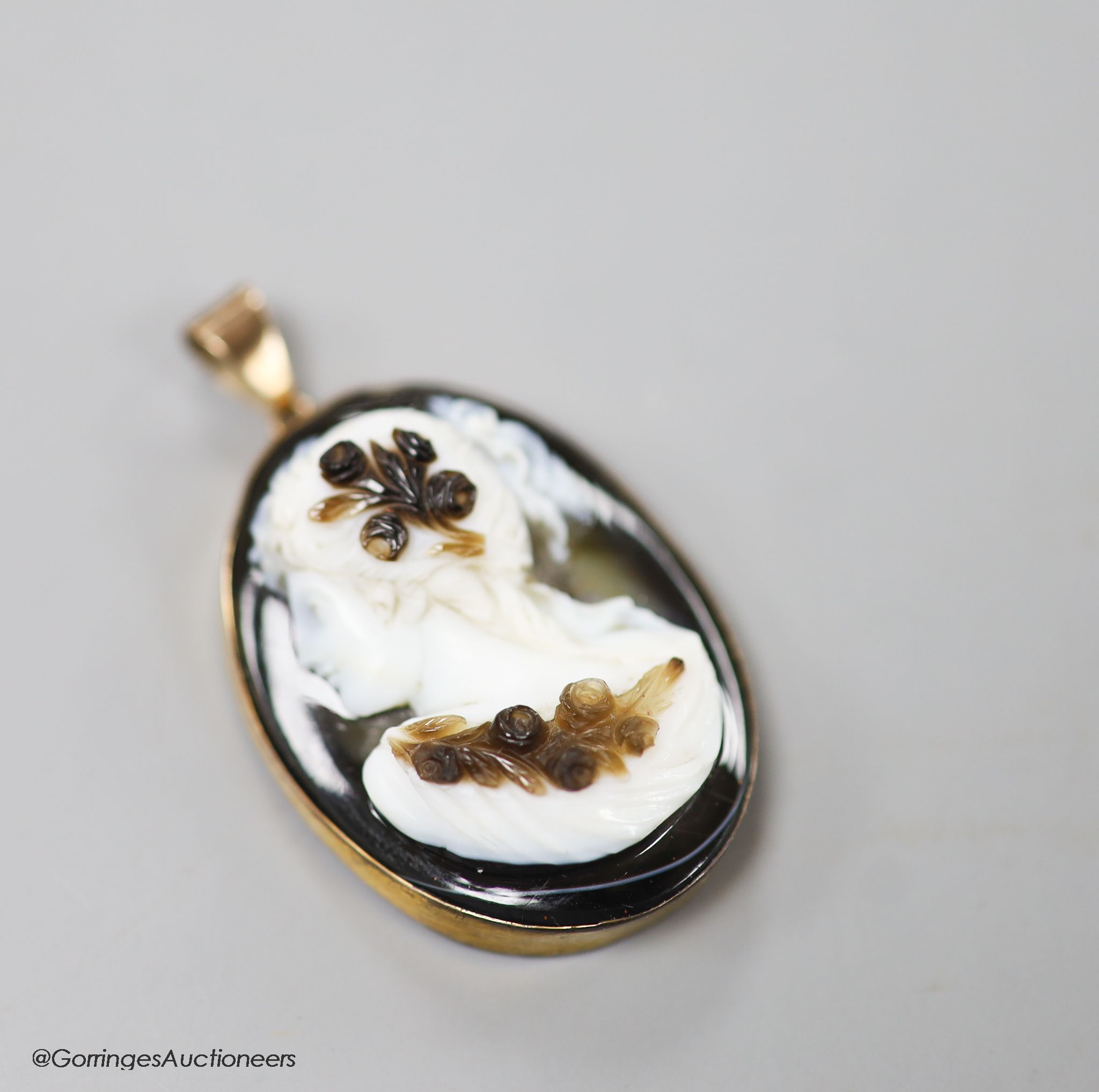 A late Victorian gilt metal mounted oval banded agate pendant, carved with the bust of a lady to dexter, agate length 35mm.